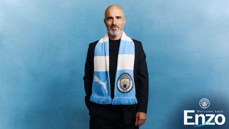 A person wearing a Manchester City scarf against a blue background with text 'Welcome back Enzo'.