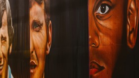 Abstract painting depicting partial faces and vivid expressions, blending vibrant colors with detailed features against a dark background.