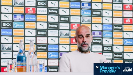 A person at a press conference with a backdrop filled with various sponsor logos including Etihad, Puma, Nexen Tire, and Revolut.