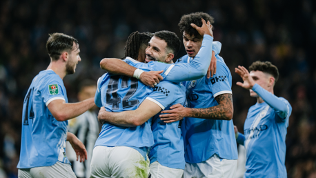 Manchester City players in blue jerseys celebrating a goal during a match.