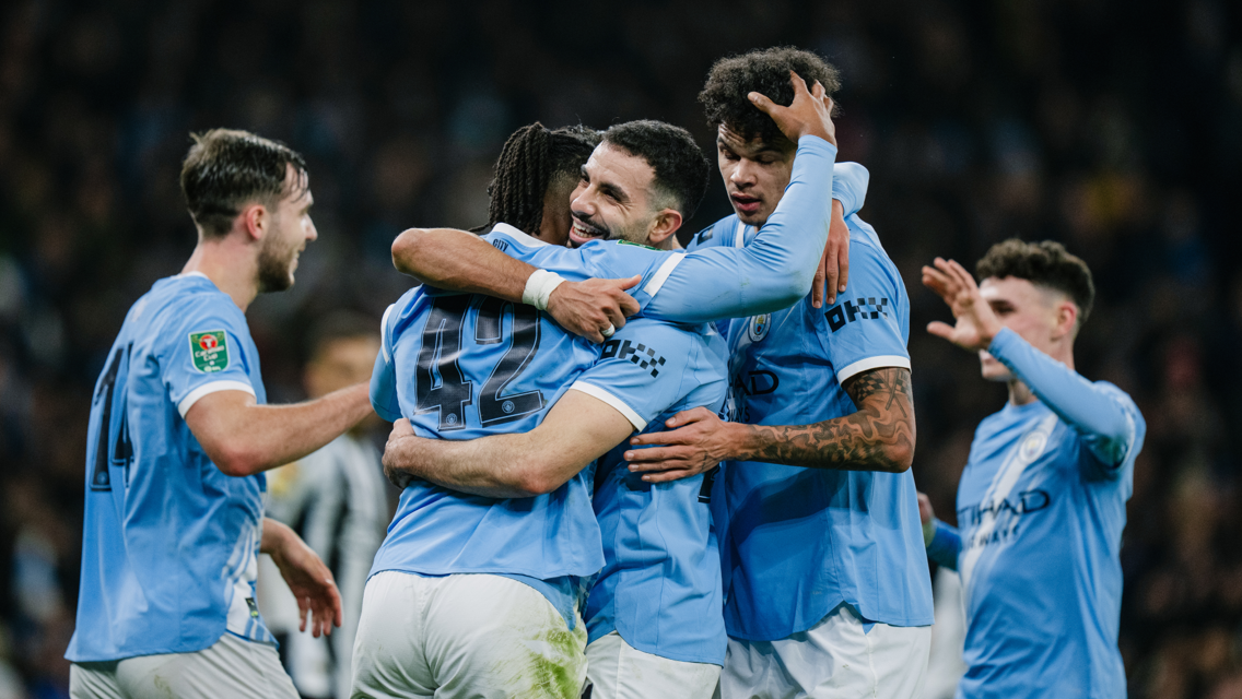 Manchester City players in blue jerseys celebrating a goal during a match.