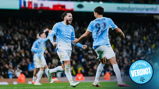 Manchester City players in a light blue kit celebrating a goal on the field during a match, with an 'Official Verdict' badge in the corner.