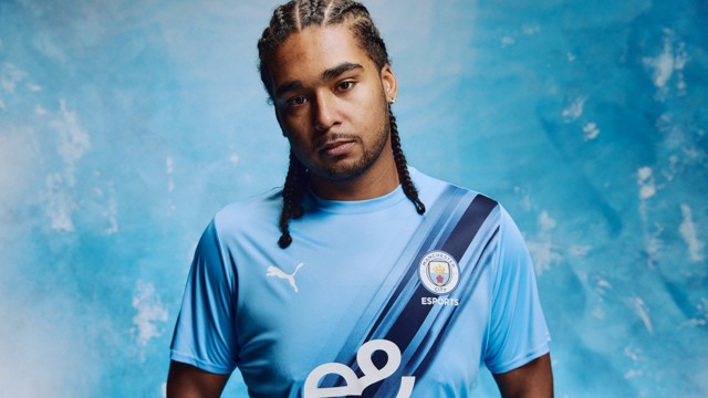 Person wearing a Manchester City Esports jersey with blurred face, light blue background