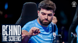 A person in a Manchester City esports jersey is seen giving a fist bump. The background features a blurred logo and the text 'BEHIND THE SCREENS.'