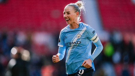 A Manchester City women's soccer player wearing a blue jersey with 'Etihad Airways' logo, running on a football field.
