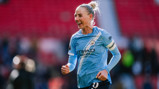 A Manchester City women's soccer player wearing a blue jersey with 'Etihad Airways' logo, running on a football field.
