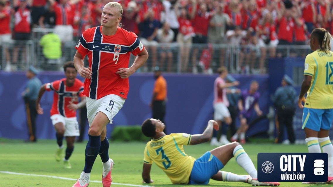 Football player from Norway celebrating a goal during a match against Brazil. The Norwegian fans are in the background. Official logos for Manchester City and FIFA are shown in the corner.