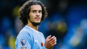 A Manchester City player wearing the team's kit, with the Premier League logo on the sleeve, clapping and facing the camera.