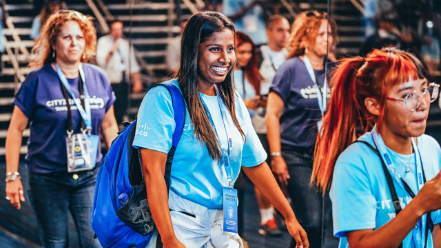 Event attendees wearing shirts with 'Cisco' and CITY branding on lanyards, walking in a venue with blurred faces for privacy.