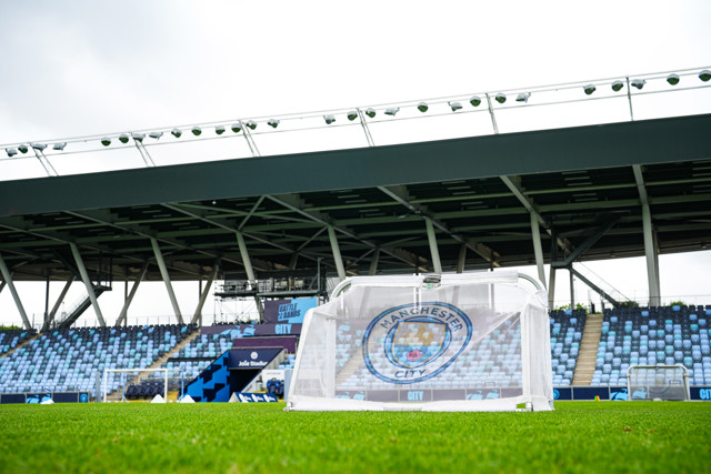 A close-up of a small goalpost with the Manchester City logo at the Academy Stadium, located on the City Football Academy grounds.