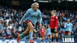A football player in a light blue Manchester City jersey celebrates during a match at a stadium. Another player in red, possibly Manchester United, is visible in the background. Text says 'Thank You Laura'.