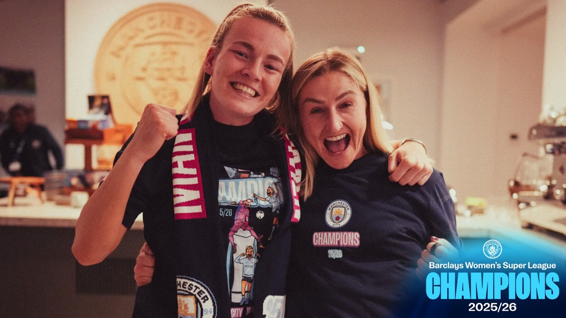 Two people wearing Manchester City merchandise celebrate the Barclays Women's Super League Championship 2025/26.