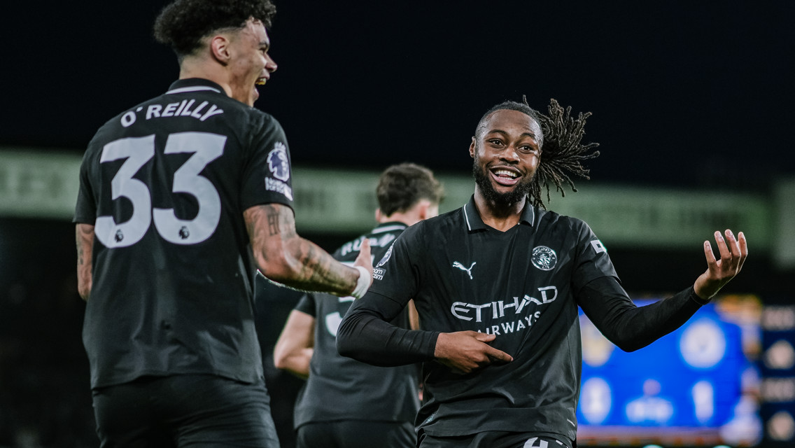 Two Manchester City players celebrating on the field, one with the jersey number 33 and the other number 42.