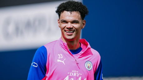 A football player wearing a pink and blue Manchester City training kit with Puma and team logos, number 33 visible.