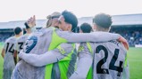 Manchester City players celebrate a goal wearing grey and neon green kits with visible Premier League logos on their backs. Numbers and names include Akanji (9), Laporte (14), and Gvardiol (24).