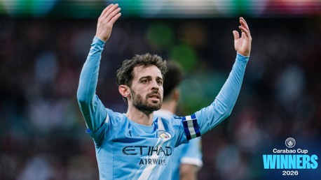 Football player in Manchester City kit celebrating with hands raised, blue captain armband, text 'Carabao Cup Winners 2026' on image.