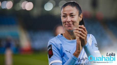 A football player in a light blue Manchester City jersey clapping. The text indicates Leila Ouahabi celebrates 100 appearances for the club.