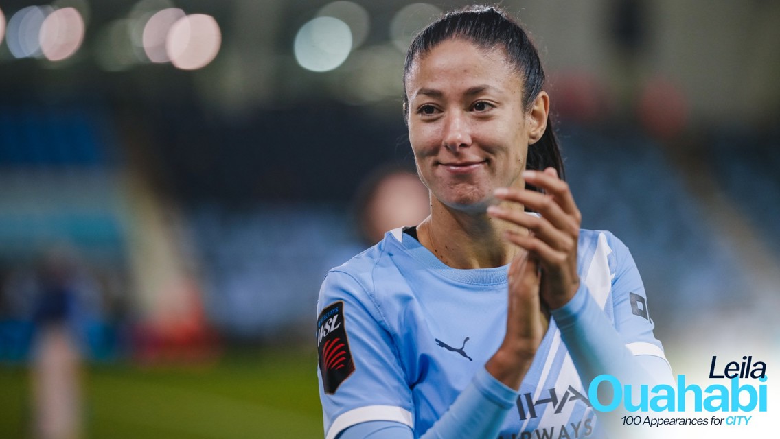 A football player in a light blue Manchester City jersey clapping. The text indicates Leila Ouahabi celebrates 100 appearances for the club.