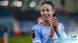 A football player in a light blue Manchester City jersey clapping. The text indicates Leila Ouahabi celebrates 100 appearances for the club.