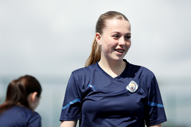 A Manchester City Women's player in a blue training kit standing outdoors during a training session.