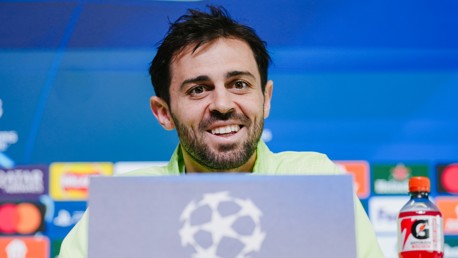 A person at a UEFA Champions League press conference with sponsor logos in the background.