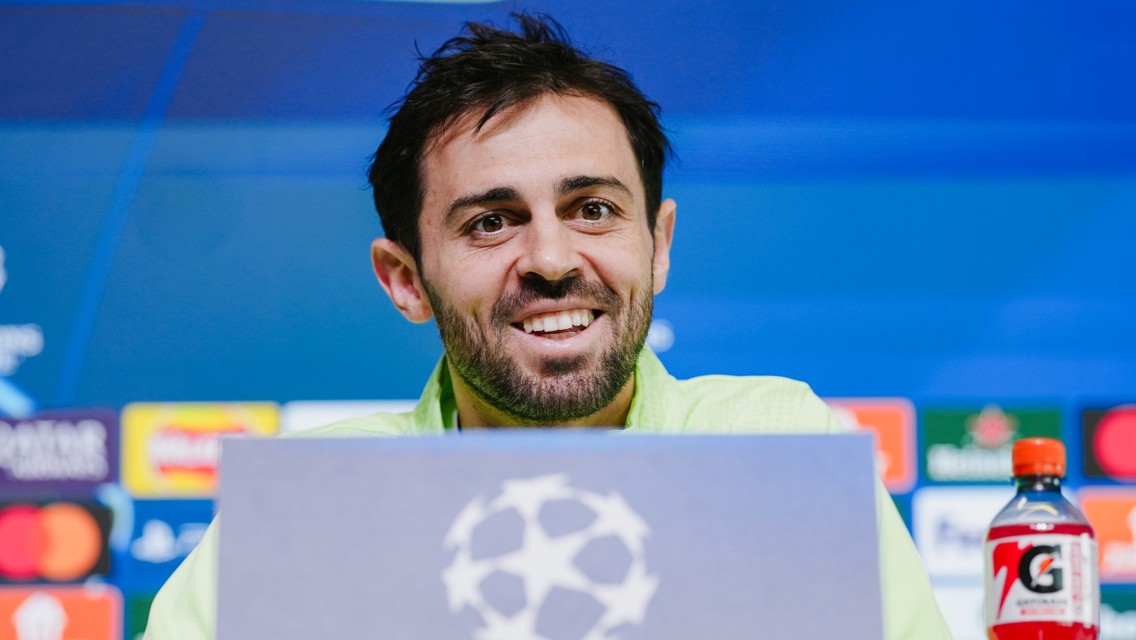 A person at a UEFA Champions League press conference with sponsor logos in the background.