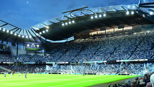 A night football match at Etihad Stadium with a large crowd and players on the field. The scoreboard shows a score of 2-0.