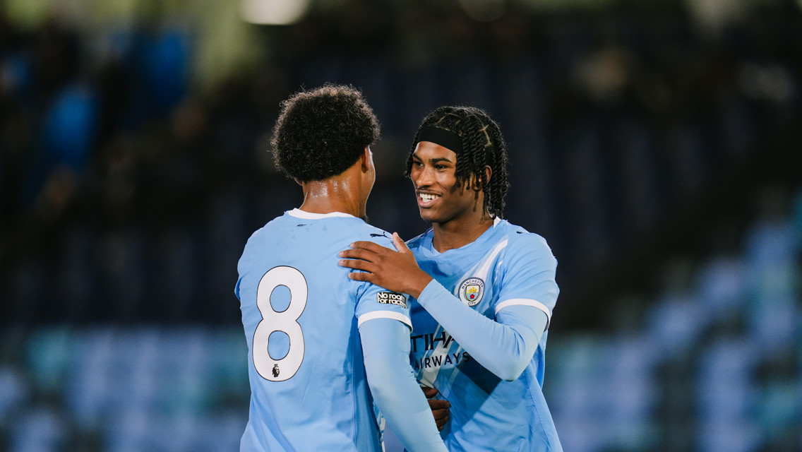 Two Manchester City players in blue jerseys with the number 8 visible on one, embracing on the field during a match.