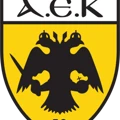 Logo of AEK FC with a black double-headed eagle on a yellow shield and 'AEK F.C.' text at the bottom.