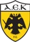 Logo of AEK FC with a black double-headed eagle on a yellow shield and 'AEK F.C.' text at the bottom.