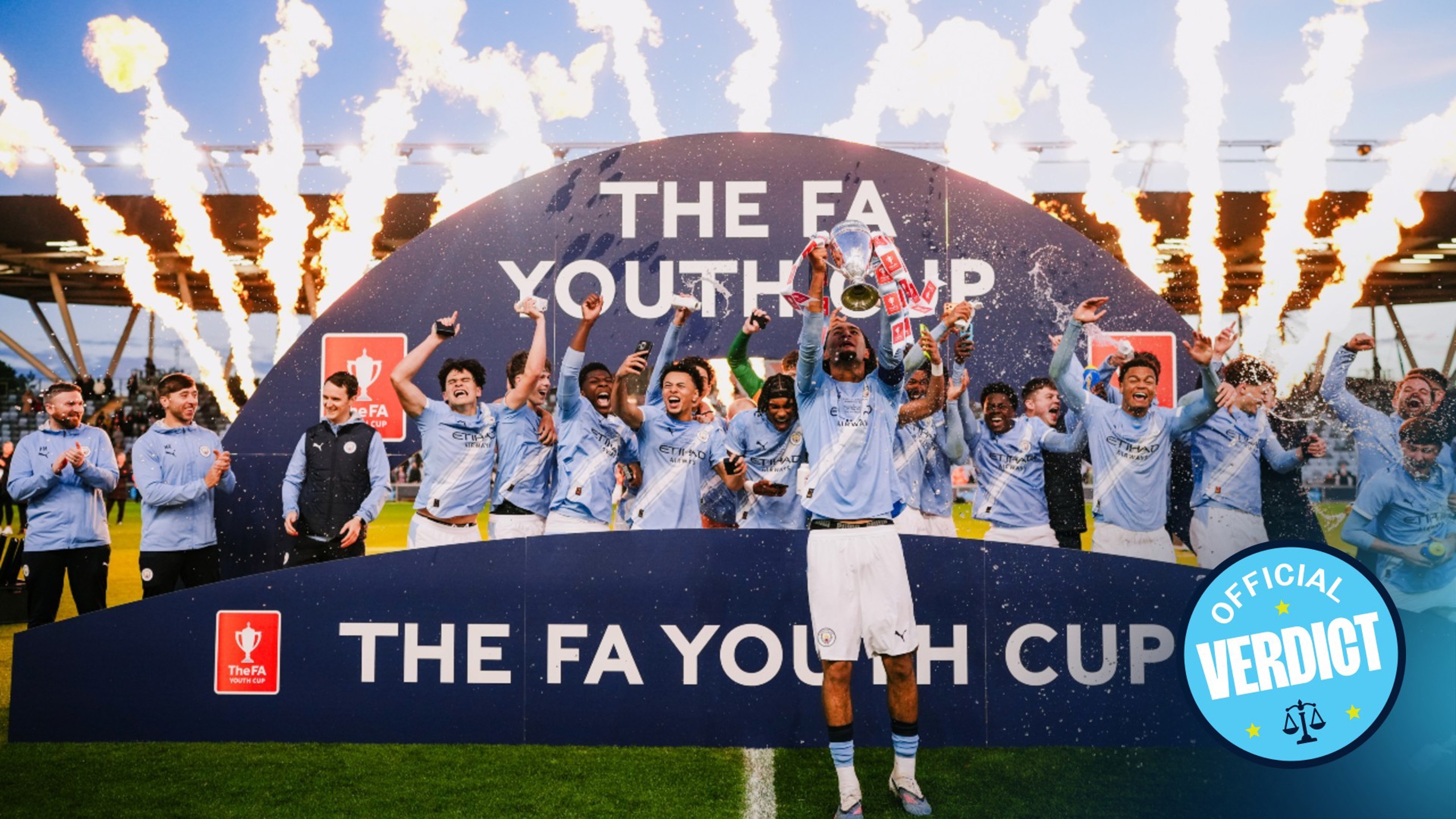 Football team celebrating their victory in the FA Youth Cup with fireworks and trophy.