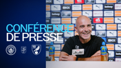 A Manchester City press conference with a smiling man speaking, bottles of Lucozade on the table, and logos of Manchester City, Carabao Cup, and Norwich City displayed.