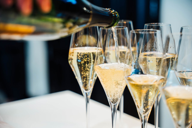 Champagne being poured into multiple tall glasses, each glass filled with bubbly champagne.