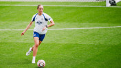 A Manchester City Women's team player in training, wearing a white and blue kit with Puma branding and playing on a grass field.