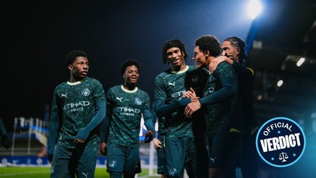 Manchester City players celebrating a goal, wearing a dark green Puma kit with Etihad Airways sponsorship. The 'Official Verdict' watermark is visible.