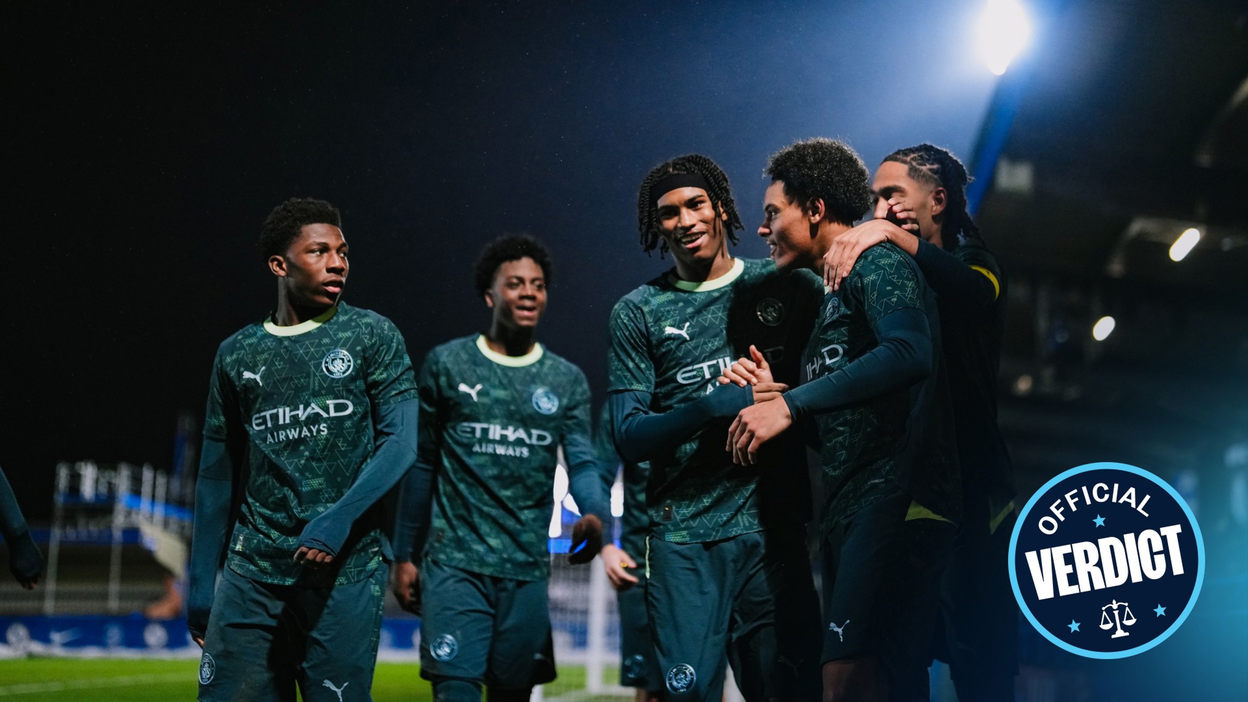 Manchester City players celebrating a goal, wearing a dark green Puma kit with Etihad Airways sponsorship. The 'Official Verdict' watermark is visible.