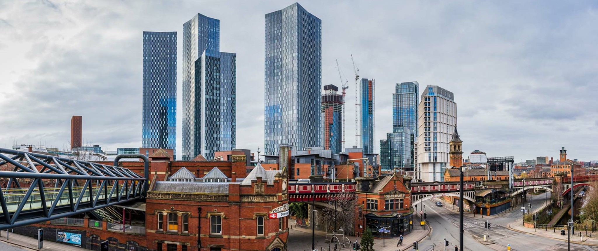 Panoramic view of Manchester skyline with tall modern buildings and historic architecture.