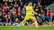 A Manchester City goalkeeper in a neon yellow kit is playing during a match, with a crowd in the background.