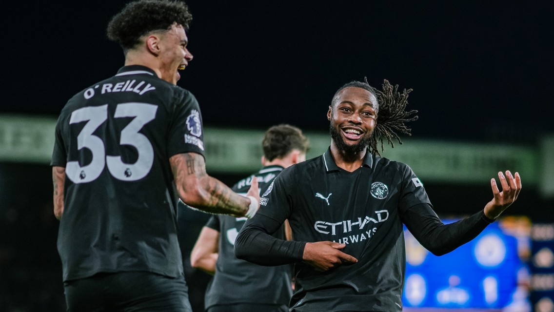 Two Manchester City players in black kits, one with a visible number 33 jersey labeled 'O'Reilly', engage in a celebratory gesture during a match.