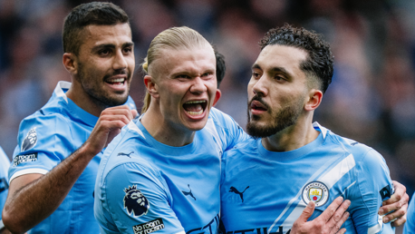 Manchester City players celebrating wearing light blue kits with team crest and Premier League patch visible.
