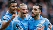 Manchester City players celebrating wearing light blue kits with team crest and Premier League patch visible.
