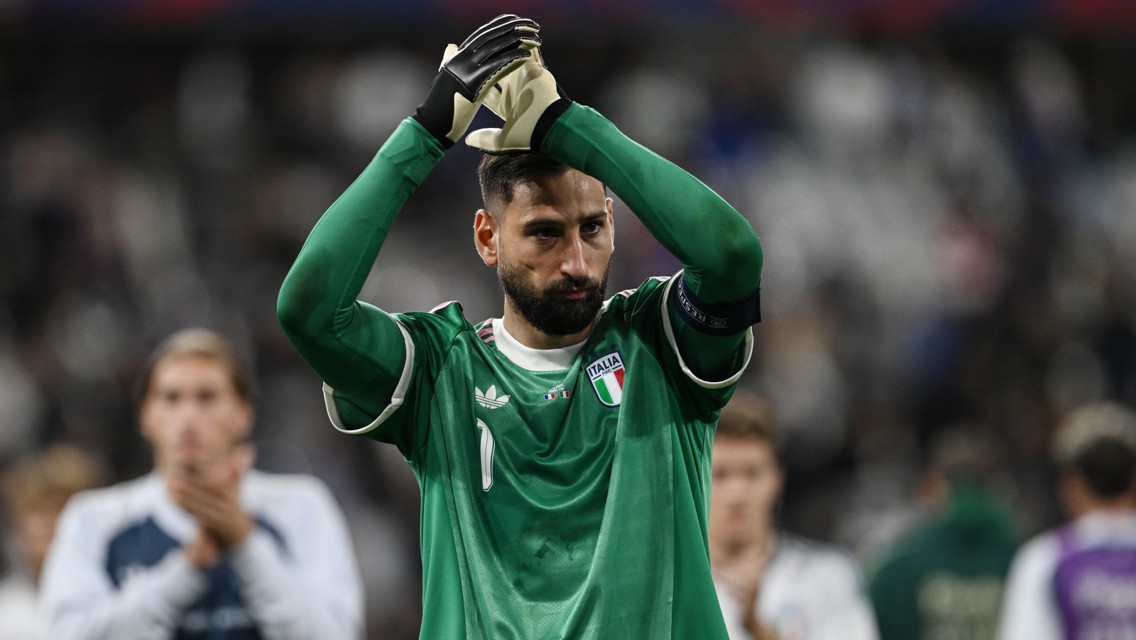 A goalkeeper in a green Italy jersey claps with gloved hands during a football match.