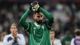 A goalkeeper in a green Italy jersey claps with gloved hands during a football match.