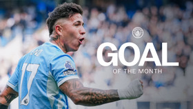 Manchester City player celebrating with 'Goal of the Month' text overlay, wearing jersey number 17. Premier League badge visible, Manchester City logo present.