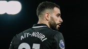 A football player seen from the back, wearing a jersey with the name 'Aït-Nouri' and Premier League logo, under bright stadium lights.