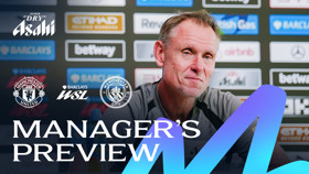 A manager giving a preview for the Manchester United vs. Manchester City match in the Barclays Women's Super League. Background shows sponsor logos and team crests.