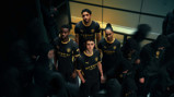 Four individuals wearing Manchester City's 2023 kit featuring Puma and Etihad Airways branding, surrounded by others in dark hoodies.