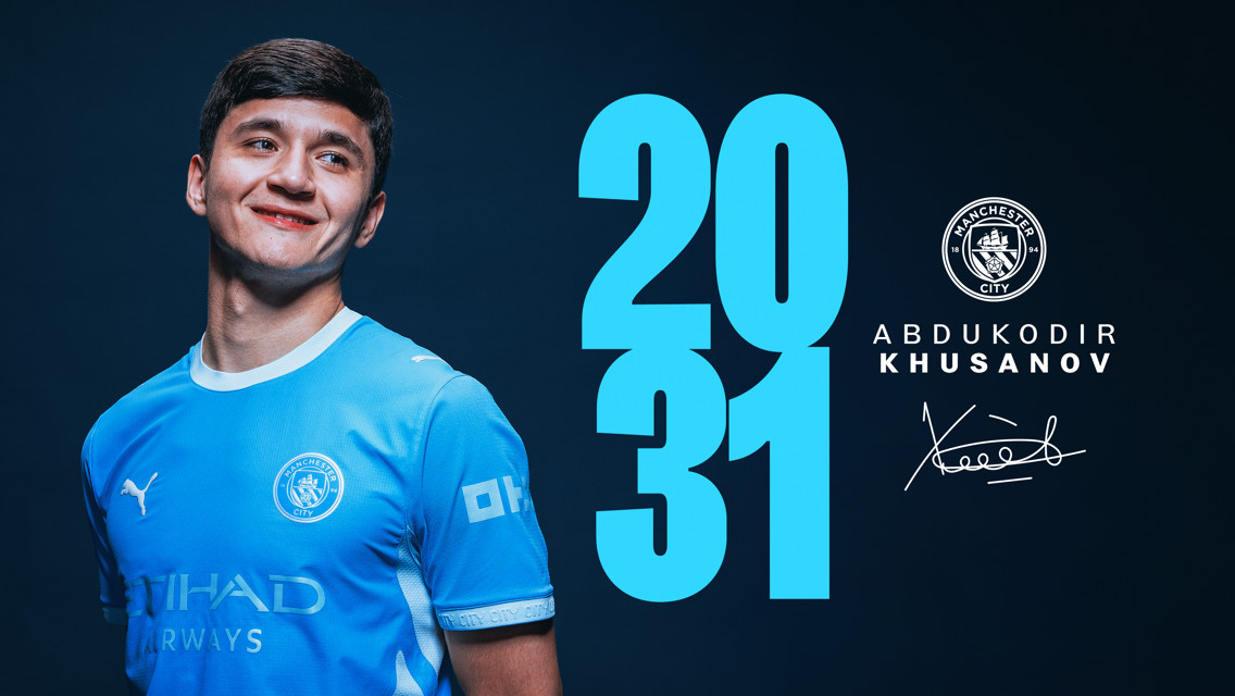 Football player in a Manchester City jersey with the year 2031 and name Abdukodir Khusanov displayed alongside club crest and signature.