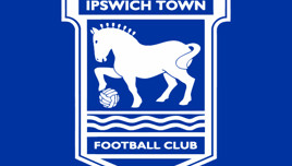 A blue and white logo of Ipswich Town Football Club featuring a horse stepping over a football with wavy lines below.