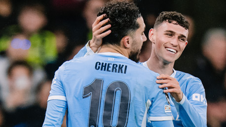 Two soccer players from Manchester City in light blue jerseys are celebrating. One player is labeled 'CHERKI' with number 10.